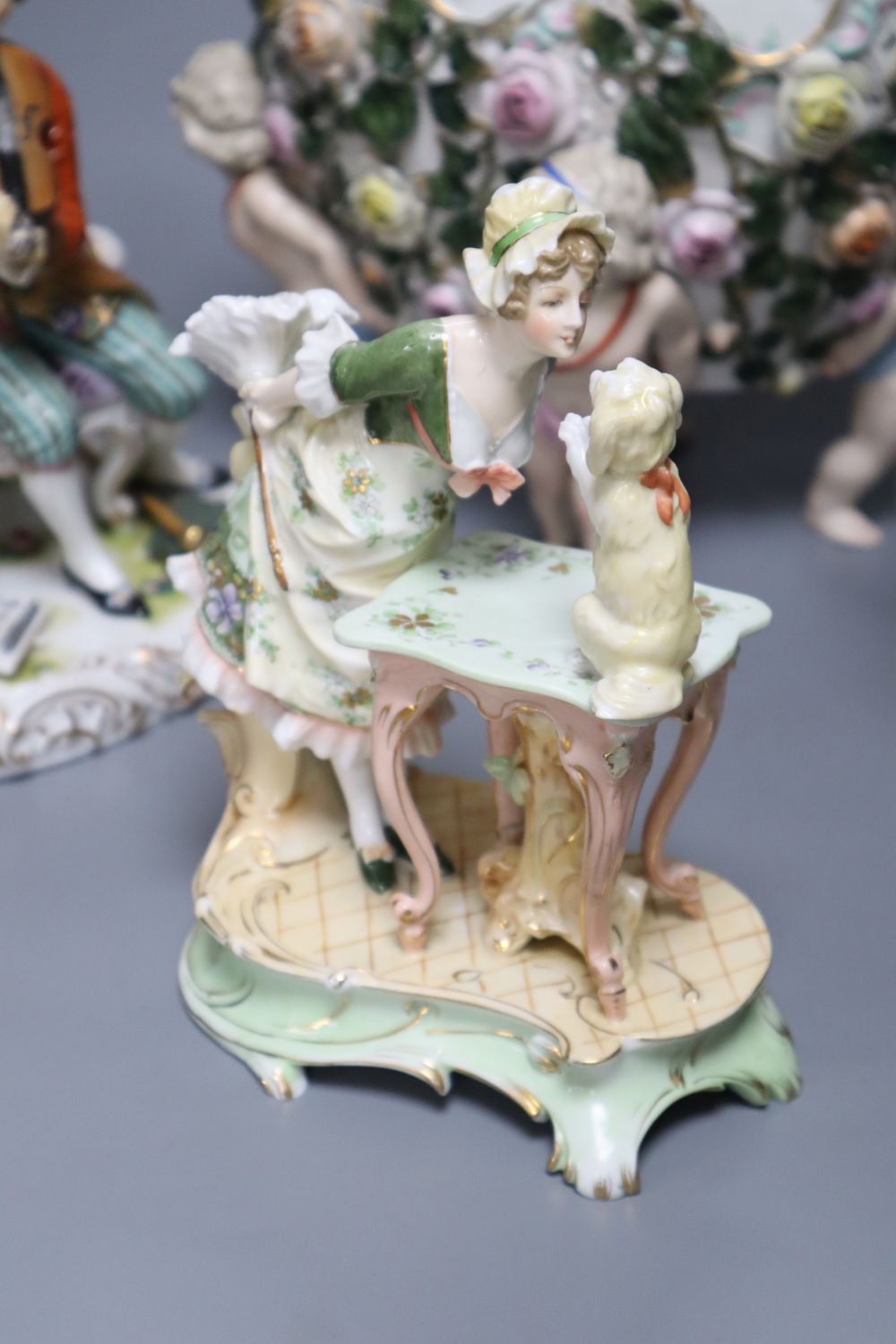 A Meissen style flower-encrusted reticulated oval porcelain jardiniere with cherub supports and three other items,